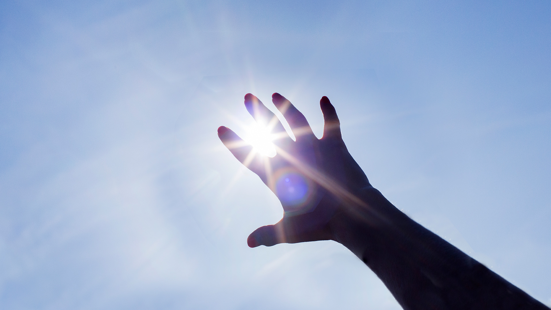 Käsi kurkottaa auringonsädettä
